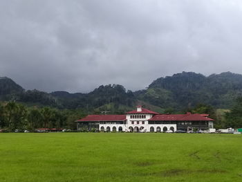 Built structure on field by mountain against sky