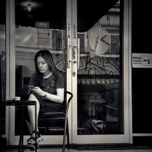 Portrait of young woman looking through window