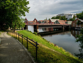 Bridge over river by buildings against sky