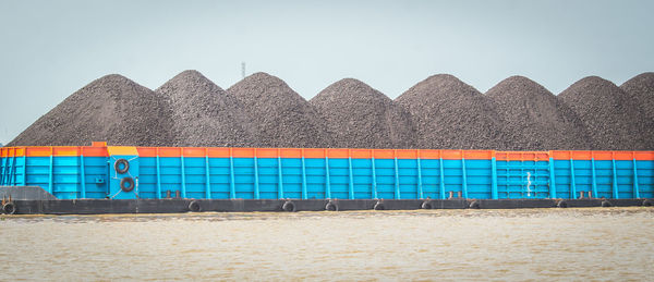 Close-up of lounge chairs on beach against clear sky