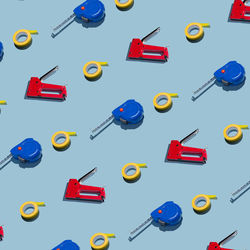 Construction staplers, measuring tape and electrical tape on a gray background, pattern