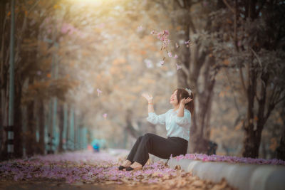 Full length of woman sitting on tree