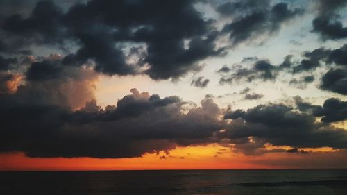 Scenic view of sea against dramatic sky during sunset