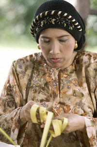 Close-up of woman weaving leaves while sitting in gazebo