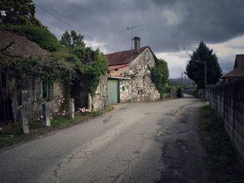 Road amidst trees and buildings against sky