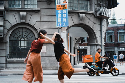 Rear view of people walking on street against buildings