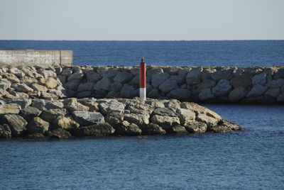 Stone wall by sea against clear sky