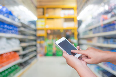 Midsection of man using mobile phone at store