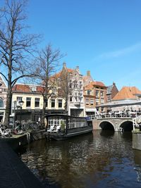 Bridge over canal by buildings against sky in city