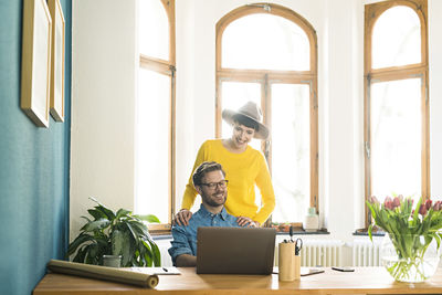 Casual entrepreneur couple in home office working at laptop and smiling