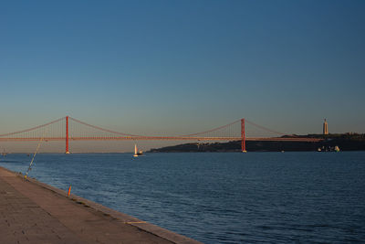 Suspension bridge over river against clear sky
