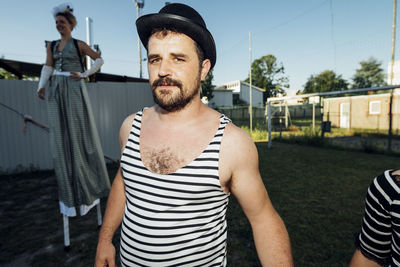 Male acrobat standing with circus performers at meadow
