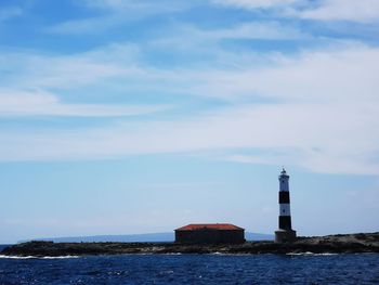 Lighthouse by sea against sky