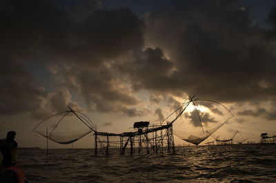 Silhouette fishing net on beach against sky during sunset