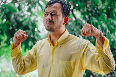 Portrait of man with arms raised standing outdoors