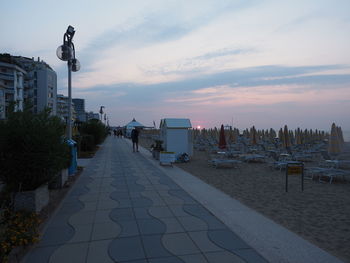 Street amidst buildings against sky during sunset