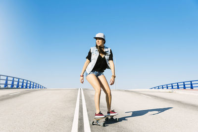 Woman skateboarding against blue sky