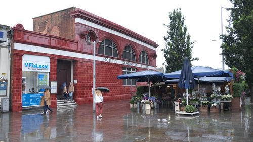 People on wet building against sky during rainy season