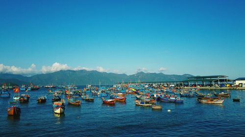 Boats moored in sea against clear blue sky