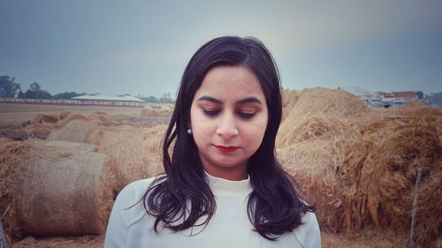 Portrait of beautiful young woman standing on land against sky