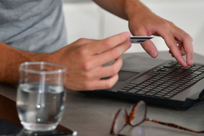 Midsection of man using laptop on table