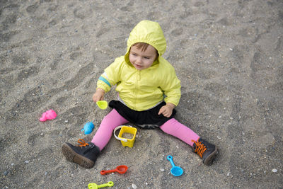 High angle view of cute baby girl playing with plastic toys at beach