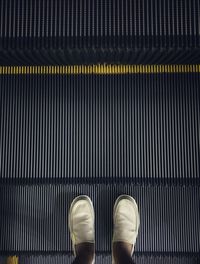 Low section of person standing on escalator