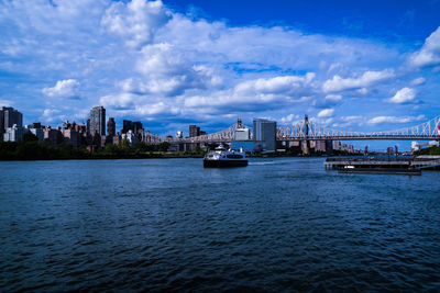 Bridge over river by buildings against sky