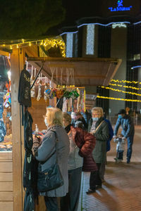 Rear view of people standing against illuminated building at night