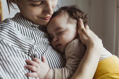 Mother looking at sleeping male toddler at home