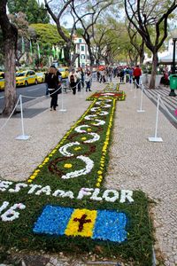 People by decorations with text on footpath in city