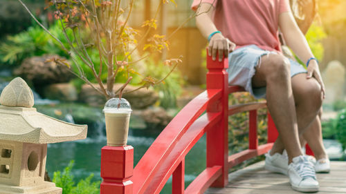 Low section of woman sitting on railing