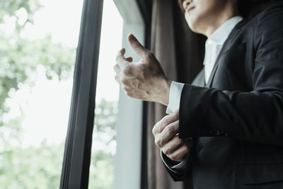 Midsection of man standing by window