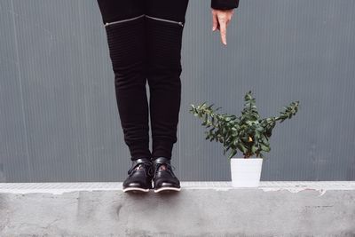 Low section of man standing by potted plant against wall