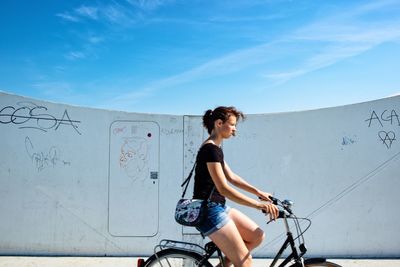 Full length of woman riding bicycle against sky