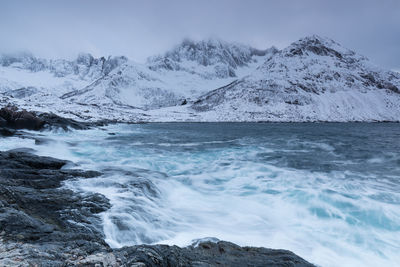 Scenic view of sea and snowcapped mountains against sky