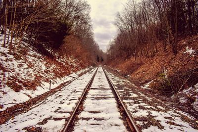 Surface level of snow covered railroad tracks against sky