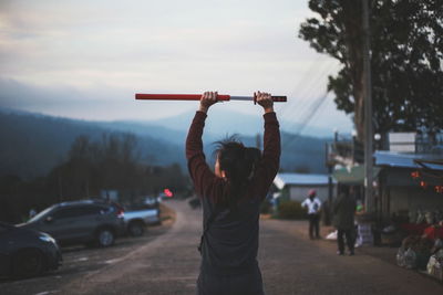 Rear view of woman holding samurai sword on road