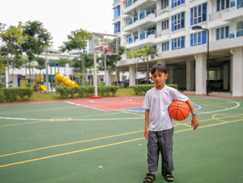 Full length of boy holding basketball at court