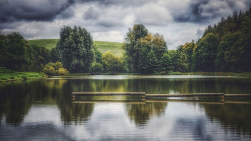 Scenic view of lake by trees against sky
