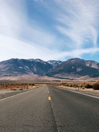 Road leading towards mountains against sky
