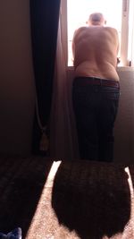 Rear view of shirtless man standing at home