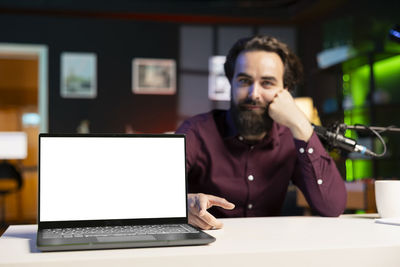 Young man using laptop at desk in office