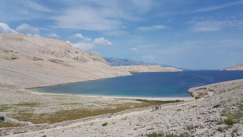 Scenic view of river and mountains against cloudy sky on sunny day