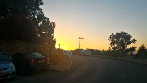 Cars parked on road at sunset