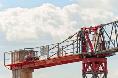 Low angle view of man standing crane against cloudy sky