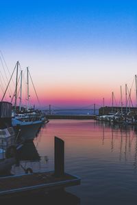 Sailboats moored in marina at sunset
