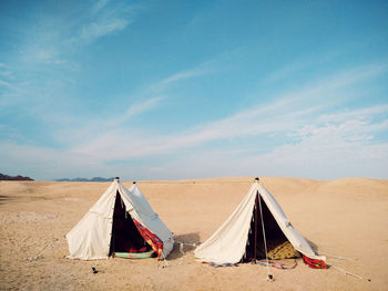 Tents at desert against blue sky