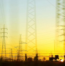 Power lines against sky at sunset