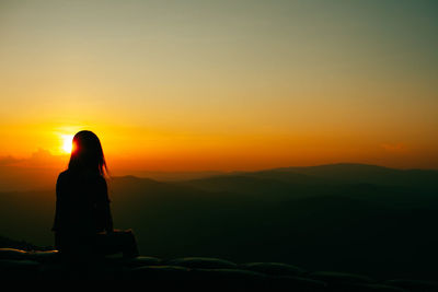 Rear view of silhouette woman looking at mountain during sunset